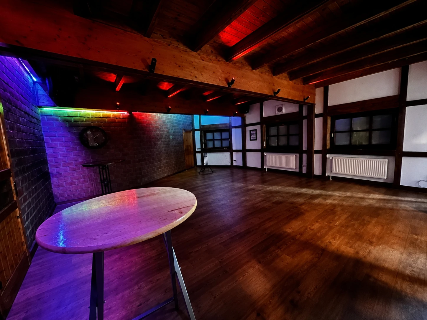 Saal mit RGB-Stimmungsbeleuchtung, Holzbalkendecke und freier Tanzfläche